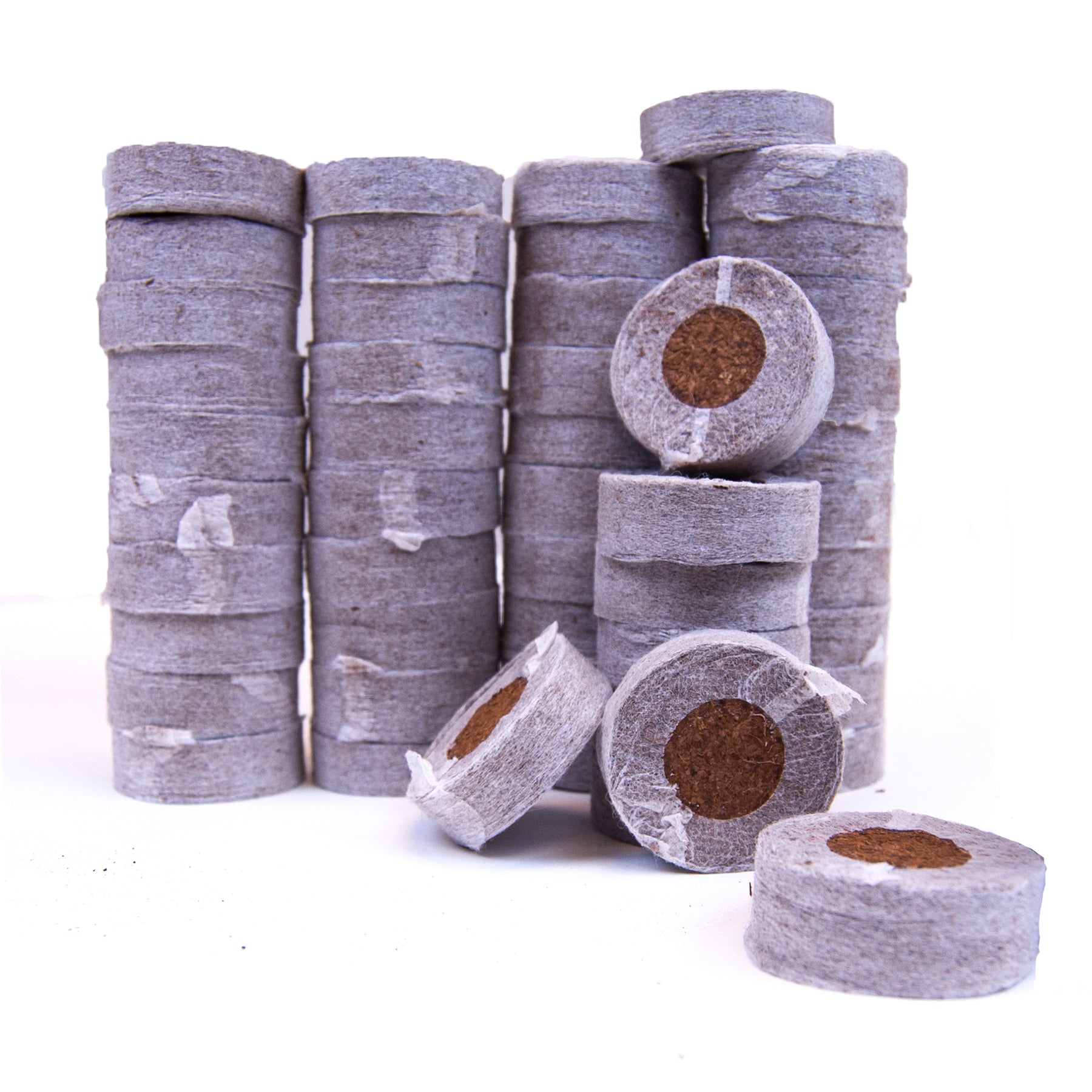 Stacks of gray coco coir seed starter plugs, with some plugs separated to show the inside.
