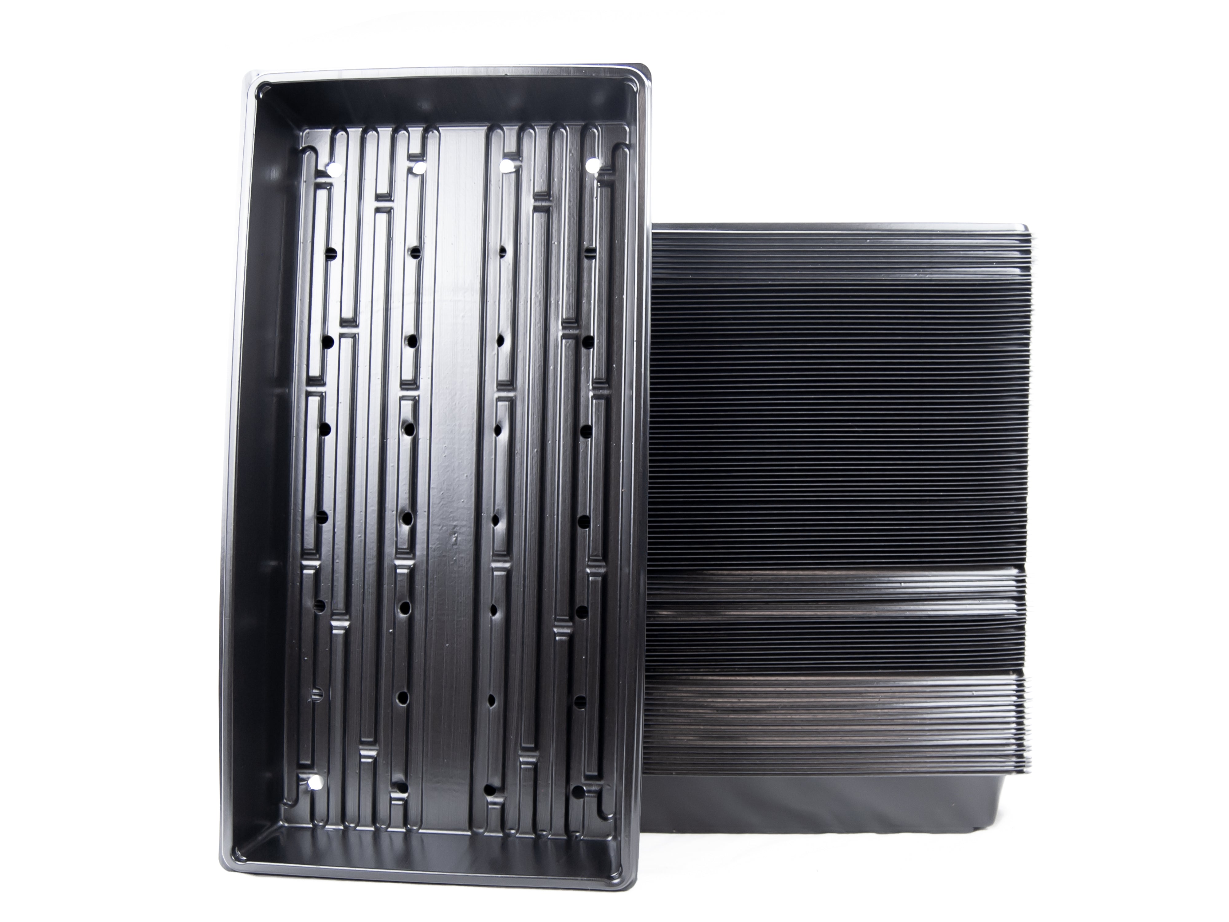 A stack of black plastic garden growing trays with drain holes.