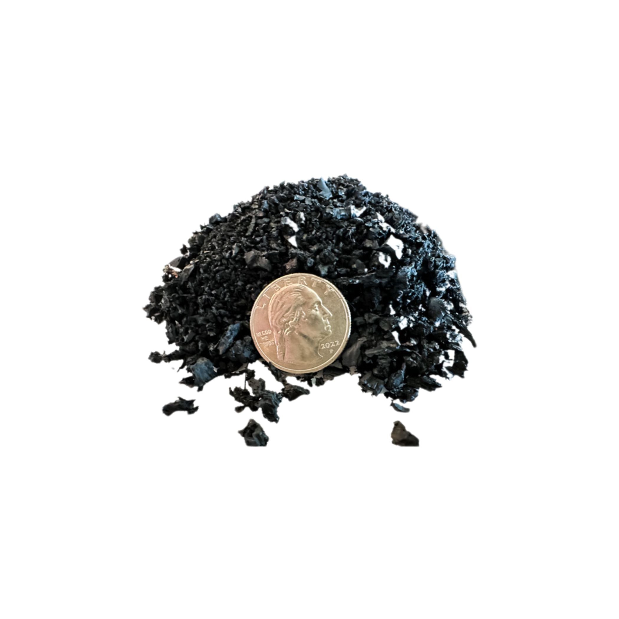 Small pile of dark material with a coin for scale on a white background